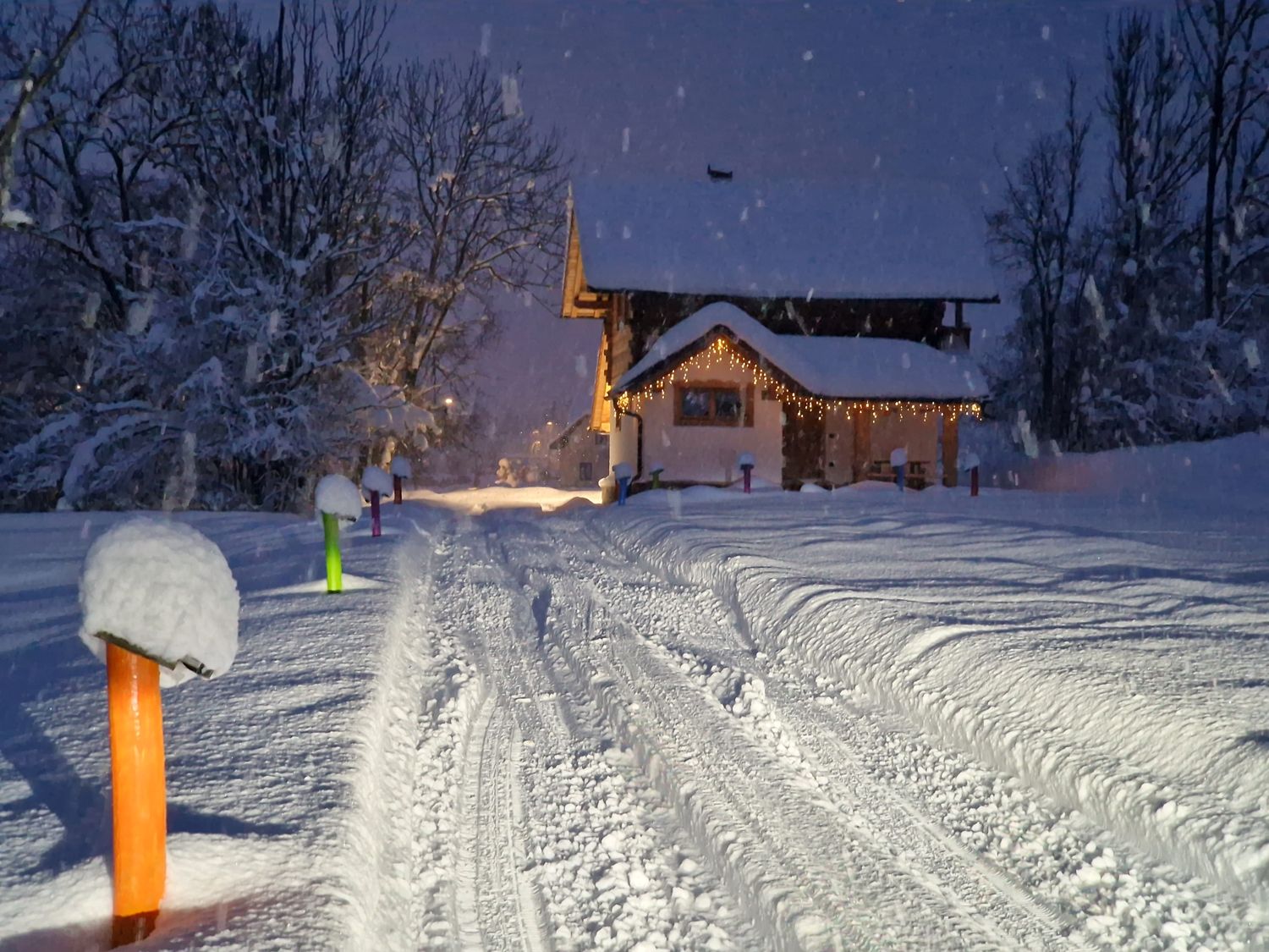 La Baita dei Colori sotto la neve, con le luci accese sotto il portico