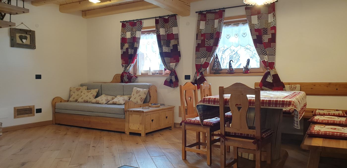 Soggiorno con divano, tavolo in legno e tende a patchwork rosse