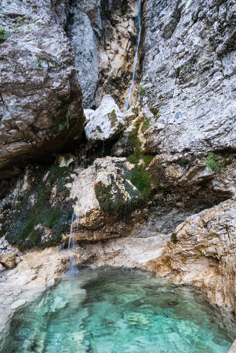 Una cascata sottile e una pozza turchese tra le rocce