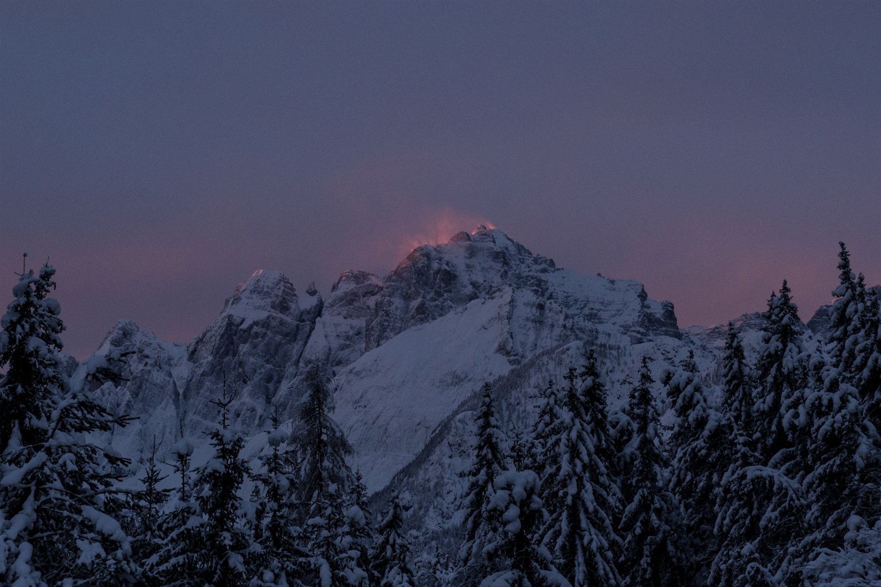 Il Jof Fuart innevato, con la vetta illuminata dalle ultime luci rosate del tramonto