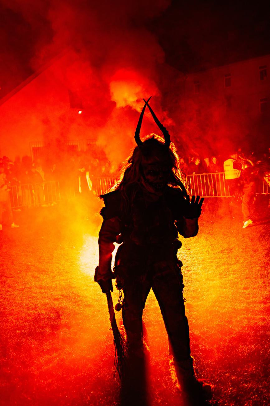 La sagoma di un Krampus con le corna e la mazza, nel fumo rosso della notte