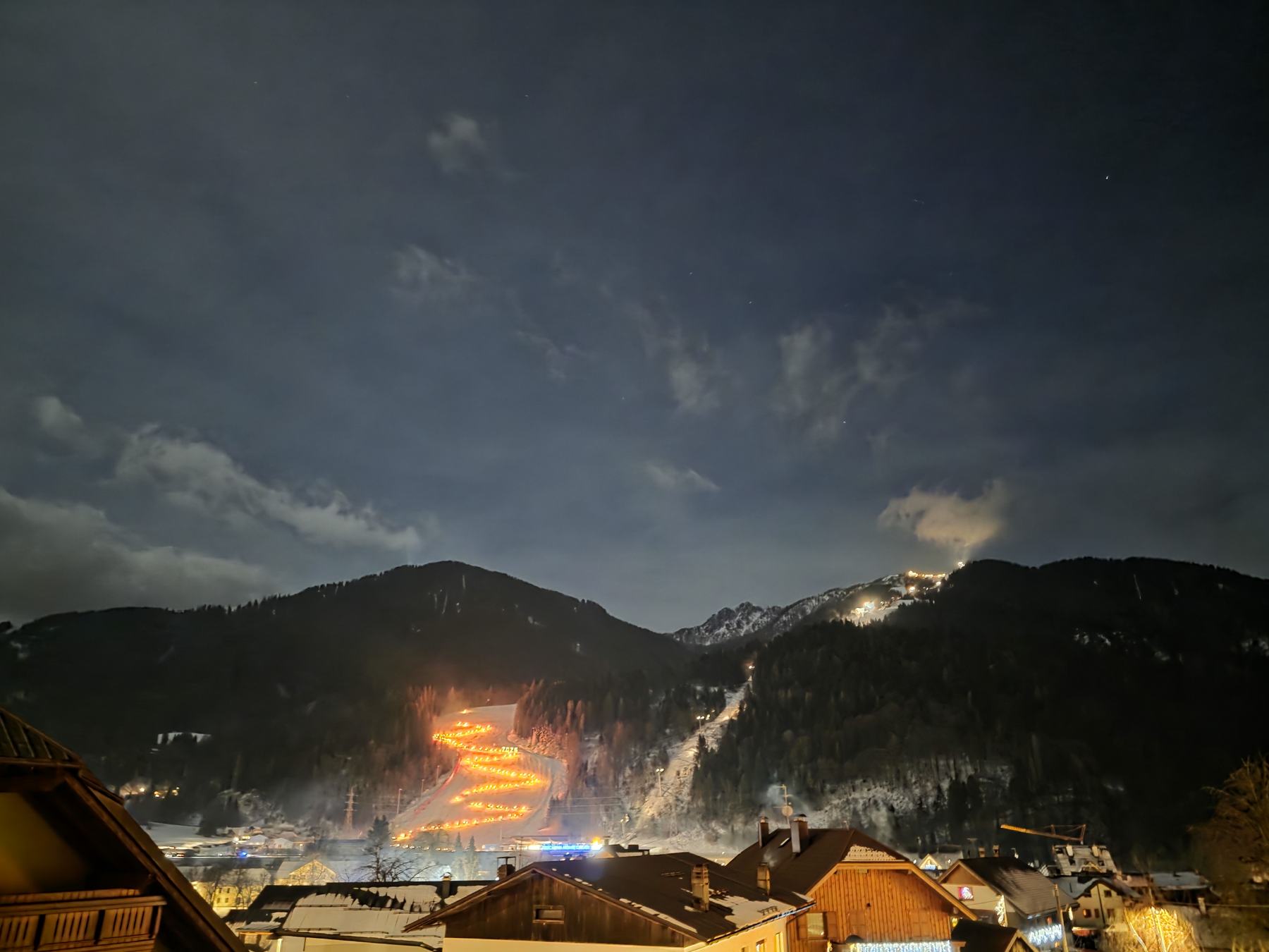 Una lunga fila di fiaccole illumina il pendio sopra il paese, nella notte d’inverno